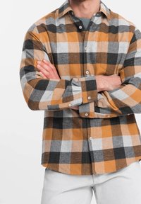 Koszula flanelowa w kratę w kolorach pomarańczowym, czarnym, szarym i białym. Posiada kołnierz zapinany na guziki, kieszeń oraz regulowane mankiety. Miękka faktura.