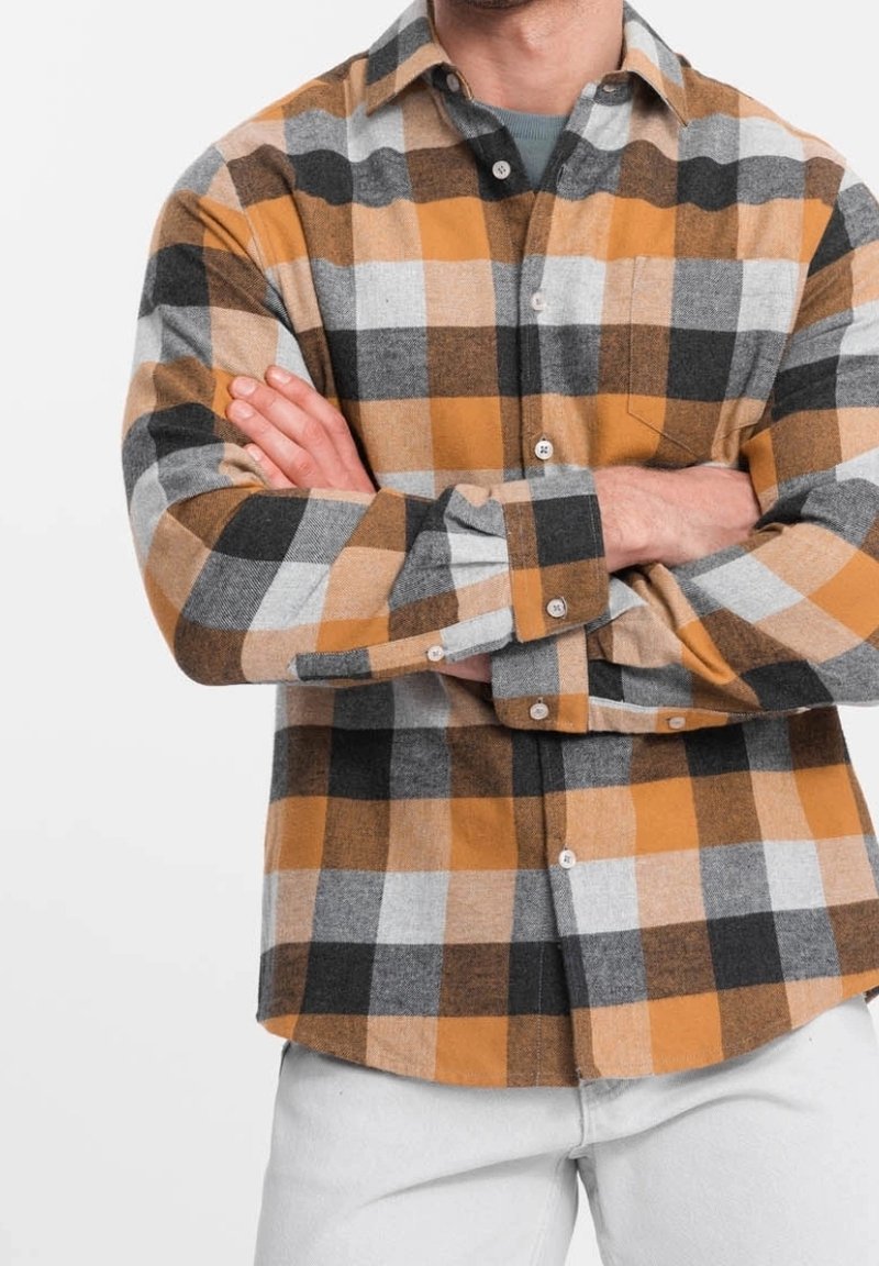 Koszula flanelowa w kratę w kolorach pomarańczowym, czarnym, szarym i białym. Posiada kołnierz zapinany na guziki, kieszeń oraz regulowane mankiety. Miękka faktura.