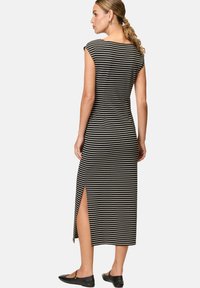 Schwarz-weißer gestreifter Midikleid mit kurzen Ärmeln und seitlichem Schlitz. Aus weichem Stoff und mit tailliertem Design, das eine glatte Textur zeigt.