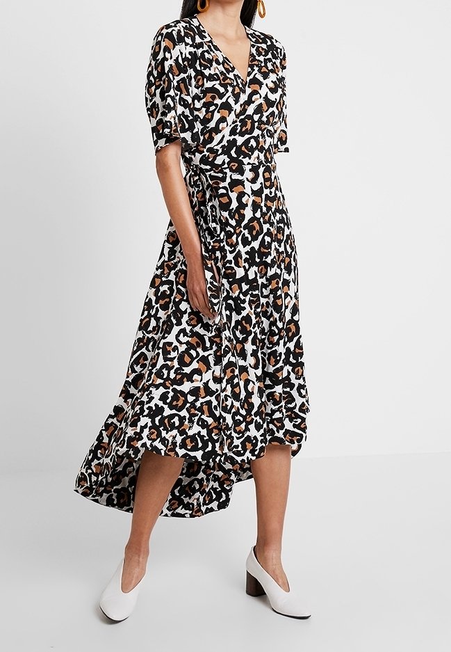 Omslag klänning med svart, vit och orange leopardmönster, korta ärmar och en hög-låg fåll, kombinerad med vita blockklackar.