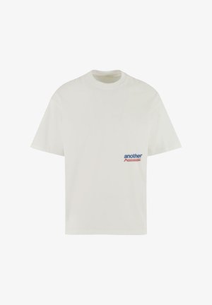 Valge puuvillane t-särk ümmarguse kaeluse ja lühikeste varrukatega. Vasakul rinnal on sinine ja punane logo tekst.