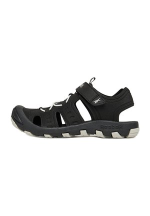 Sandalo outdoor aperto Reebok nero con lati ritagliati, cinturino in velcro, lacci elastici bianchi e suola robusta bianca e nera.