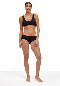 Schwarzer Sport-BH und passende Unterhosen mit orangefarbenem, gebrandetem Bund. Glatte Stoffqualität, sportliches Design, Rundhals und breite Träger.