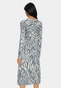 Rochie midi cu mânecă lungă, cu o siluetă ajustată, dintr-un material alb care prezintă un model cu dungi zebră negre. Material texturat cu detalii pliate.