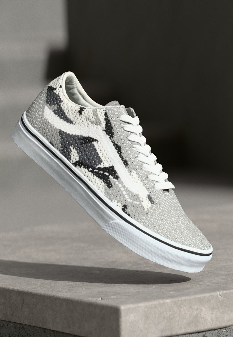 Gray and white sneaker with a textured mesh upper, black accents, laces, and a white rubber sole featuring a black stripe.