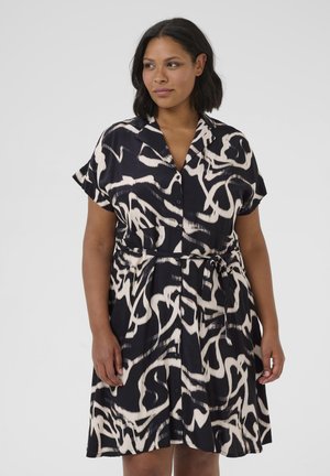 Short-sleeve dress featuring a bold black and white abstract pattern, button-down front, and belted waist. Made of lightweight fabric.