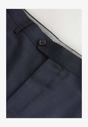 Pantaloni navy con design a vita piatta, tasca anteriore e chiusura con bottone nero. L'interno presenta un accento in tessuto a righe sulla cintura.