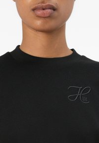 Svart sweatshirt med rund halsringning och korta ärmar. Har en ton-i-ton broderad "HUGO"-logotyp på bröstet. Slät textur.