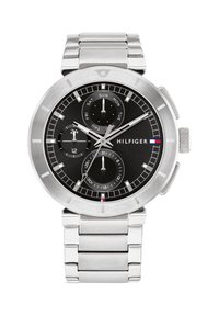 Montre en acier inoxydable argenté avec un cadran noir, trois sous-cadrans pour le jour, la date et le format 24 heures, et une lunette polie. Présente le logo Hilfiger.