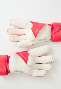 Párnázott, piros és fehér kapuskesztyűk ujjvédővel, textúrázott tapadással, rugalmas mandzsettával, és "Vapor Grip 3" márkázással a hátsó részen.