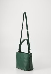Borsa a spalla in pelle verde con superficie texturizzata, tracolla regolabile e tasca laterale, caratterizzata da un design minimale e una forma rettangolare.