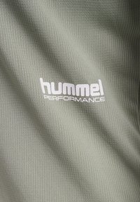 Tissu gris clair texturé avec logo blanc "hummel PERFORMANCE" imprimé sur la surface.