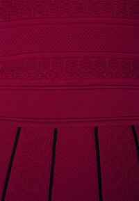 Robe en tricot bordeaux avec des panneaux horizontaux texturés, des motifs complexes et des rayures noires au niveau de l'ourlet. Finition lisse dans l'ensemble.