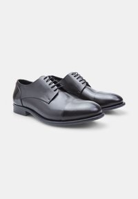 Scarpe eleganti in pelle nera con finitura liscia, design con allacciatura, punta rotonda e tacco basso. Presentano dettagli di cucitura delicati sulla parte superiore.