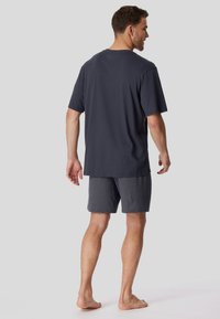Herren T-Shirt in Marineblau mit kurzen Ärmeln, kombiniert mit gemusterten, knielangen Shorts in Marineblau und Weiß, die einen bequemen Sitz bieten.