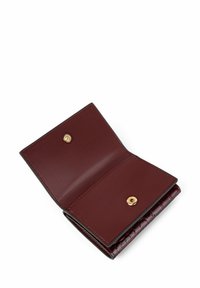 Portfel z bordowej skóry z teksturowanym akcentem wytłaczanym w kształcie krokodyla. Wyposażony w złote zapięcie na zatrzask oraz gładkie, wewnętrzne przegrody. Kompaktowy design.