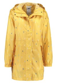 Gul regnrock med ett mönster av vattendroppar i blått och grått. Har dragsko i midjan, huva och knäppning med knappar. Slät, vattentät tyg.