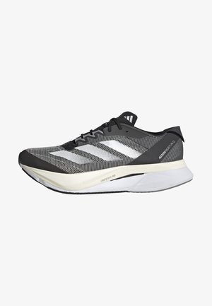 Sort og hvid atletisk sko med en mesh-overdel, har tre hvide striber, en fremtrædende sål mærket "LIGHTSTRIKE PRO" og et strømlinet design.
