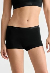 Black cotton hipster shorts with a smooth elastic waistband, featuring a fitted design. No visible patterns or hardware details.