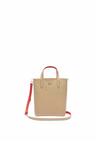 Sac à main en cuir texturé beige avec un design vertical simple, une bandoulière rouge et deux poignées courtes. Présente un petit accent de logo.