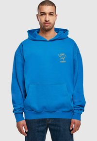 Sudadera azul de tela suave, con un bolsillo frontal y un gráfico dorado en el lado izquierdo del pecho. Incluye una capucha grande y puños acanalados.