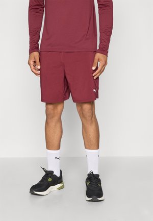 Maroon long-sleeve shirt paired with maroon athletic shorts. Black sneakers with green accents and white crew socks. Clean design, smooth texture.
