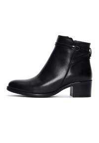 Bottine en cuir noir avec petit talon carré, sangle décorative avec boucle argentée et fermeture éclair latérale.