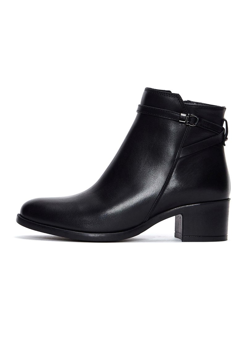 Bottine en cuir noir avec petit talon carré, sangle décorative avec boucle argentée et fermeture éclair latérale.