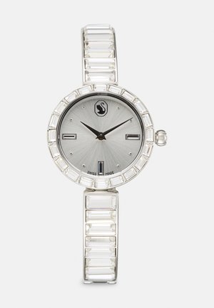 Silberne Uhr mit rundem Zifferblatt, grauem Zifferblatt, rechteckigen Stundenmarkierungen und einem kristallbesetzten Gehäuse. Klarer Acrylarmband mit geometrischen Gliedern.