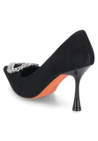 Černá semišová vysoká bota na podpatku s špičatou špičkou, s akcentem ve tvaru sponky osazené rhinestony a oranžovou podrážkou. Podpatky mají elegantní design.