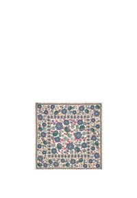Alfombra cuadrada de algodón con un patrón floral que presenta tonos de azul, verde y rojo sobre un fondo blanco, bordeada por un borde texturizado.