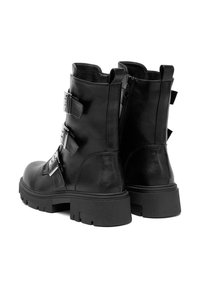 Czarne botki za kostkę na masywnej podeszwie z trzema srebrnymi klamrami po boku i zamkiem błyskawicznym z tyłu.