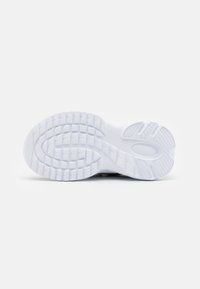 Suela de zapato deportivo blanca con goma texturizada. Presenta un patrón ondulado, ranuras para tracción y un talón redondeado para estabilidad.