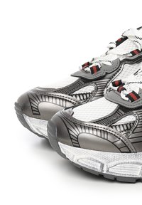 Sportsko-sko i hvid og metallic grå med mesh-overdel, teksturerede detaljer, sort og rød snøring, og en polstret sål.