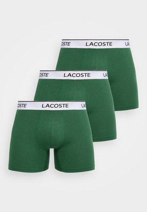 Három zöld férfi boxeralsó fehér elasztikus derékpánttal, mindegyiken fekete "LACOSTE" felirat.