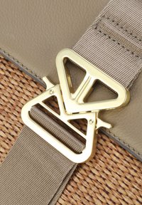 Beige læder- og vævet strå crossbody-taskestrop med en guldfarvet, trekantet metalspænde og en struktureret tan stropp.