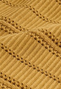 Tissu jaune en maille avec des motifs côtelés et de dentelle créant des rayures verticales et des détails ajourés texturés.
