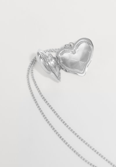 Pendente a forma di cuore in argento con superficie lucida, dotato di apertura a cerniera e di una catena con anelli intrecciati.