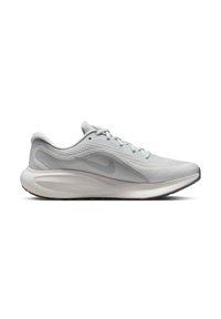 Zapatilla de running gris claro con parte superior de malla, cordones planos, suela acolchada y un diseño curvado distintivo. Presenta un logo en el lateral y un patrón texturizado.
