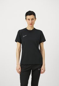 Crna atletska majica kratkih rukava od materijala koji odvodi vlagu, s okruglim izrezom. Bijeli Nike logo na lijevoj strani prsiju.