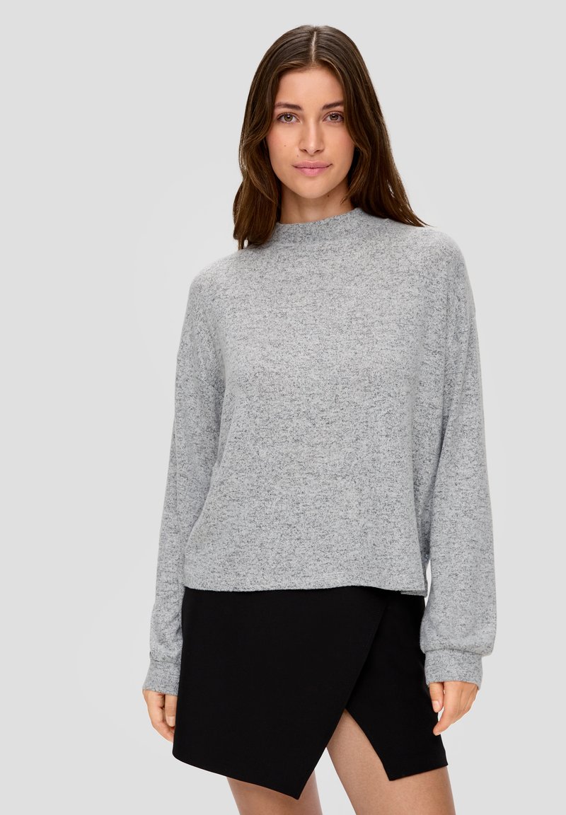 Jasnoszary sweter z długim rękawem i okrągłym dekoltem, o miękkiej fakturze, zestawiony z czarną spódnicą wrap z skośnym dołem.