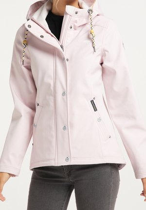 Femme portant une veste à capuche rose clair avec boutons-pression, fermeture éclair, cordon de serrage à la capuche et poches latérales sur un pantalon foncé.