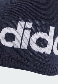 Navy knit beanie with white lettering. Made of soft fabric, features a ribbed hem, and has a large logo across the front.