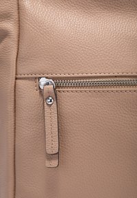 Beige leren tassectie met zichtbare textuur, een zilveren rits met een stoffen trekband, en gedetailleerde stiksels langs de randen.