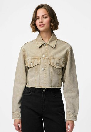 Veste en denim beige raccourcie avec un col pointu, deux poches avant, boutons en argent, ourlet effiloché et manches longues, associée à un pantalon noir.