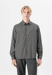 Langermet skjorte med knapper i et mørkegrått og kremfarget rutemønster. Myk stoff med klassisk krage og frontknapper.