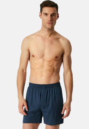 Dunkelblaue Baumwollboxershorts mit einem elastischen Bund, die ein dezentes strukturiertes Muster und einen Knopfverschluss vorne aufweisen.