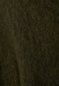 Textil de lână verde închis cu o suprafață moale și texturată. Prezintă un aspect pufos, ușor înmălțat, în nuanțe variate de verde.