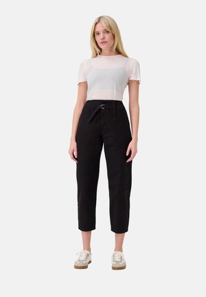 Zwarte high-waisted broeken met een tailleband, taps toelopende benen en een opgerolde zoom, gecombineerd met een lichtgrijze shirt met korte mouwen en crèmekleurige sneakers.