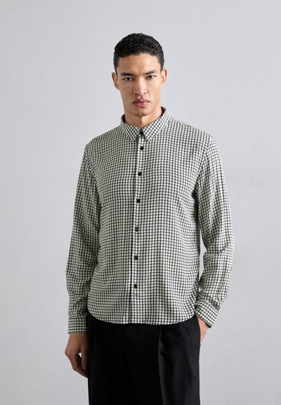 Long-sleeve button-up shirt in black and white grid pattern, featuring a pointed collar and black buttons, made from textured fabric.